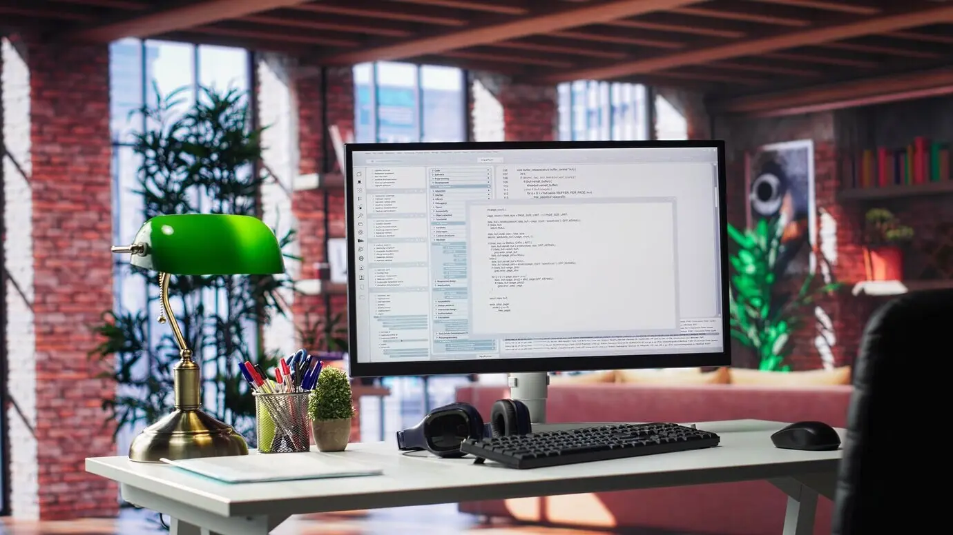 Пустой настольный монитор, используемый для разработки программного обеспечения и написания кода в роскошной современной квартире-лофте.